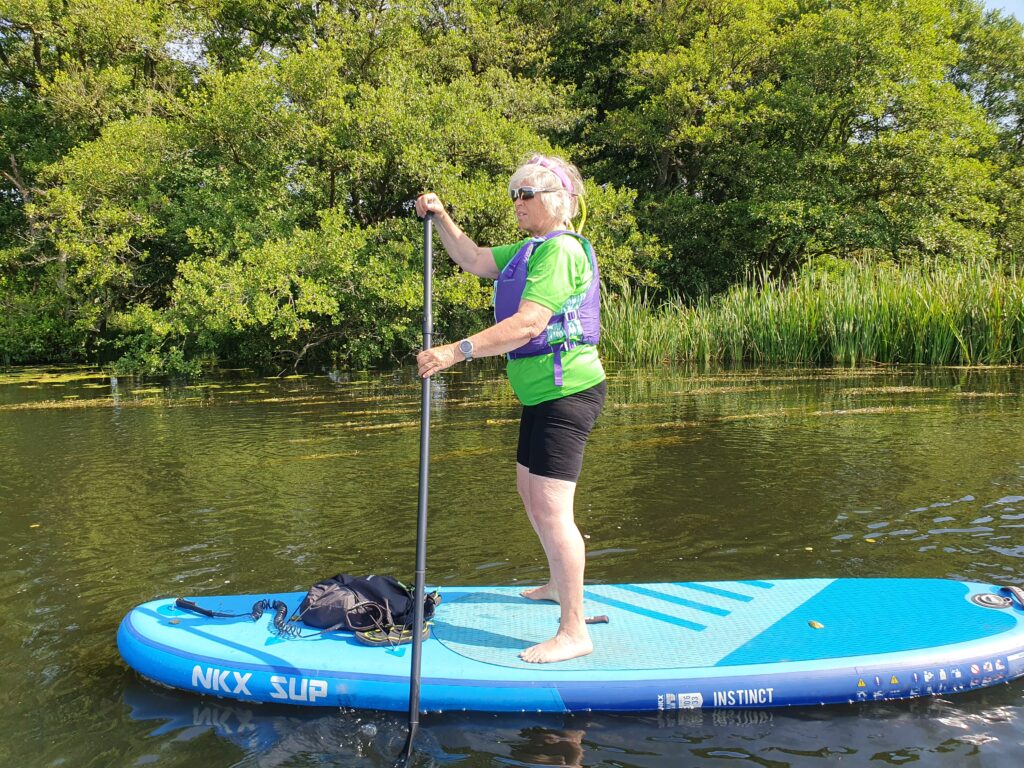 Kvinde på SUP med træer som baggrund